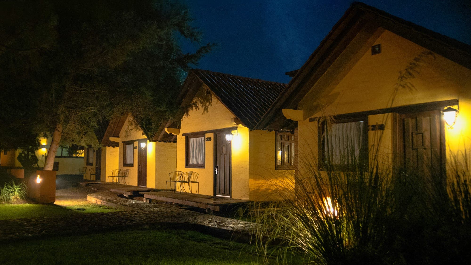 Complejo de cabañas iluminadas de noche, con galerías de madera